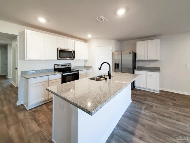 a large white kitchen with sink a microwave and cabinets