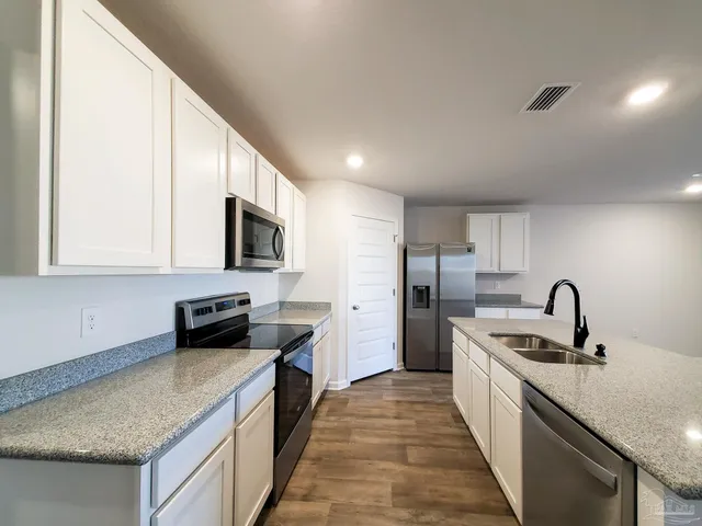 a kitchen with stainless steel appliances granite countertop a sink stove microwave and refrigerator