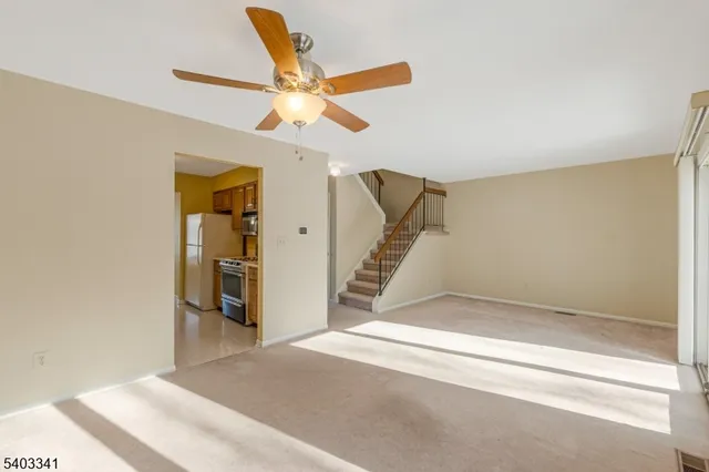 a view of an empty room with wooden floor and a ceiling fan