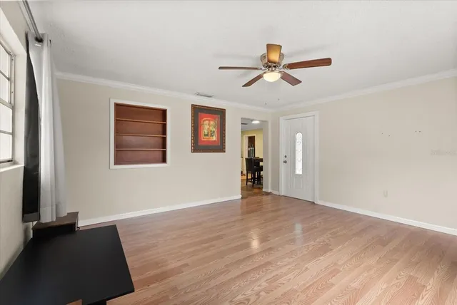 a view of empty room with wooden floor and fan