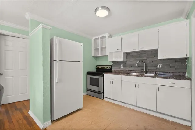 a kitchen with stainless steel appliances granite countertop a refrigerator a stove a sink and white cabinets