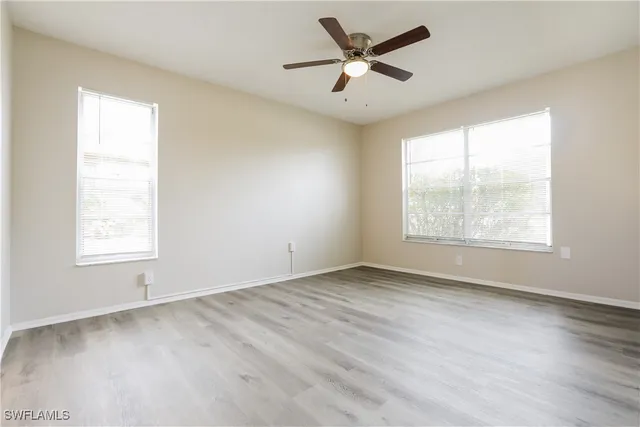 a view of an empty room with a window and wooden floor
