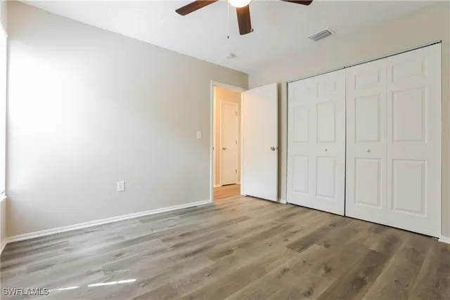 an empty room with a ceiling fan and wooden floor