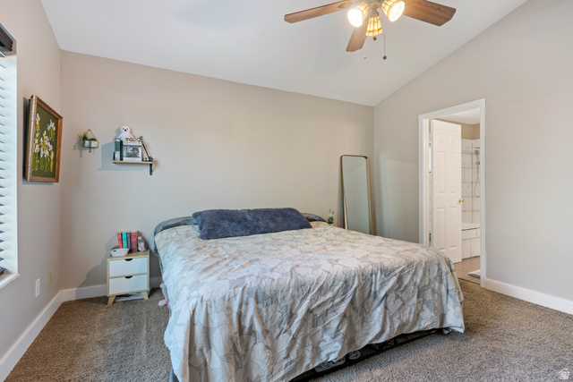 790 East Fiddlers Canyon Road Cedar City, UT 84721 - Photo 15 of 35 Carpeted bedroom featuring a vaulted ceiling, a ceiling fan with light fixture, window with blinds, and an entryway to an attached bathroom with a tiled shower
