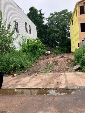 a view of a white house with large trees next to a road