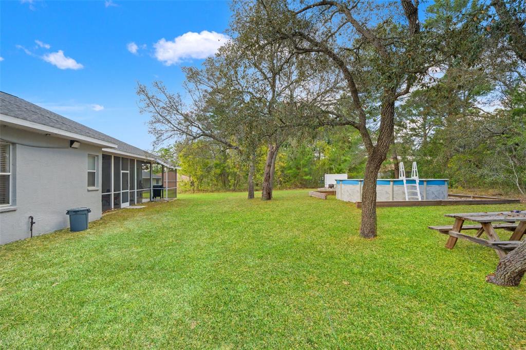 11128 Lomita Wren Road Weeki Wachee, FL 34614 - Photo 31 of 39 a view of a house with a backyard and a tree