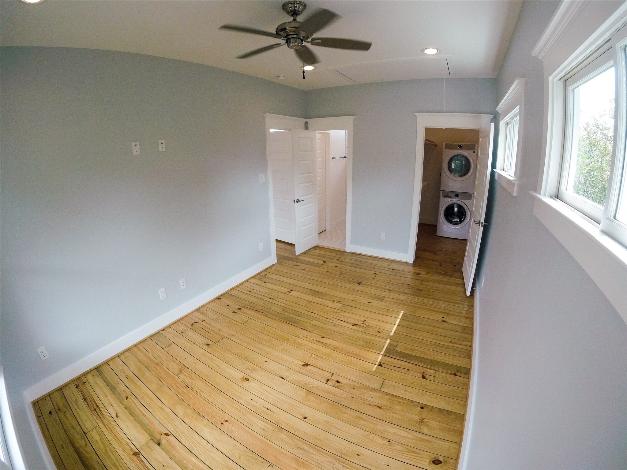 210 Tabor Street Houston, TX 77009 - Photo 14 of 18 Bright bedroom with hardwood floors, light gray walls, and a ceiling fan. Multiple windows allow natural light.