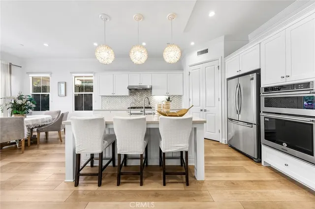 a large kitchen with stainless steel appliances a large counter top a stove and a wooden floors