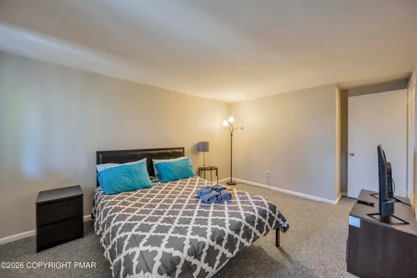 a bedroom with a bed and a flat tv screen on a dresser