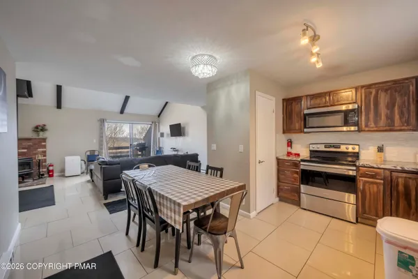 a kitchen with stainless steel appliances granite countertop a stove top oven a sink dishwasher a dining table and chairs with wooden floor