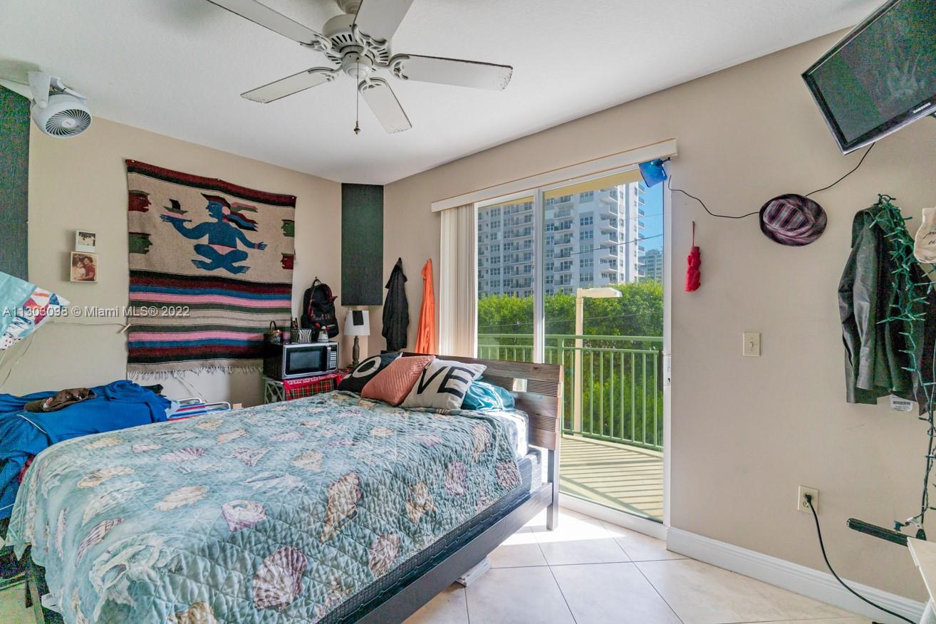 3210 Northeast 5th Street, Unit 203 Pompano Beach, FL 33062 - Photo 28 of 34 a bedroom with a bed and a chandelier