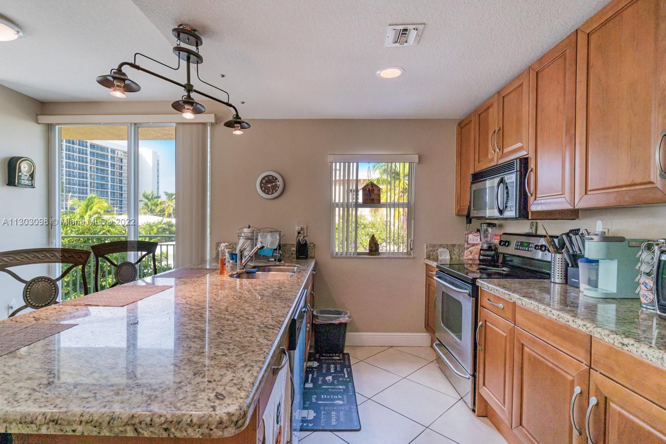 3210 Northeast 5th Street, Unit 203 Pompano Beach, FL 33062 - Photo 5 of 34 a large kitchen with granite countertop a sink a counter top space appliances and cabinets