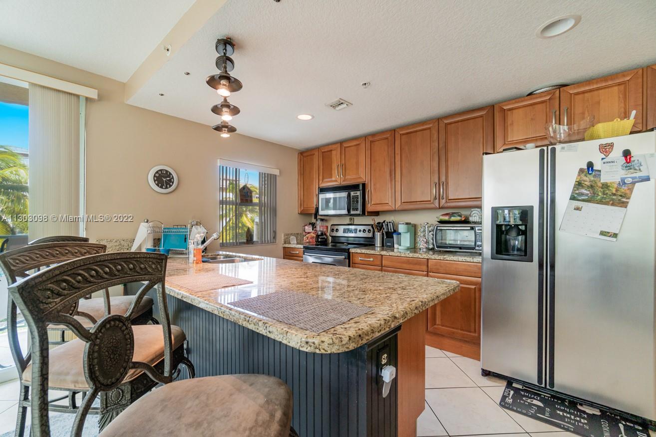3210 Northeast 5th Street, Unit 203 Pompano Beach, FL 33062 - Photo 6 of 34 a kitchen with stainless steel appliances granite countertop a table chairs refrigerator and microwave
