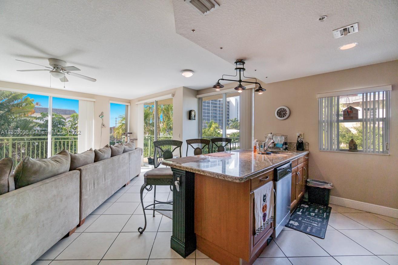 3210 Northeast 5th Street, Unit 203 Pompano Beach, FL 33062 - Photo 7 of 34 a living room with kitchen island furniture and a chandelier