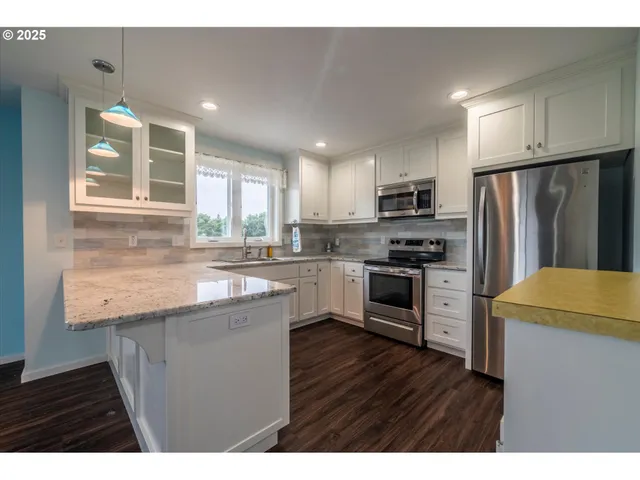 a kitchen with granite countertop a refrigerator a stove top oven a sink and dishwasher with wooden floor