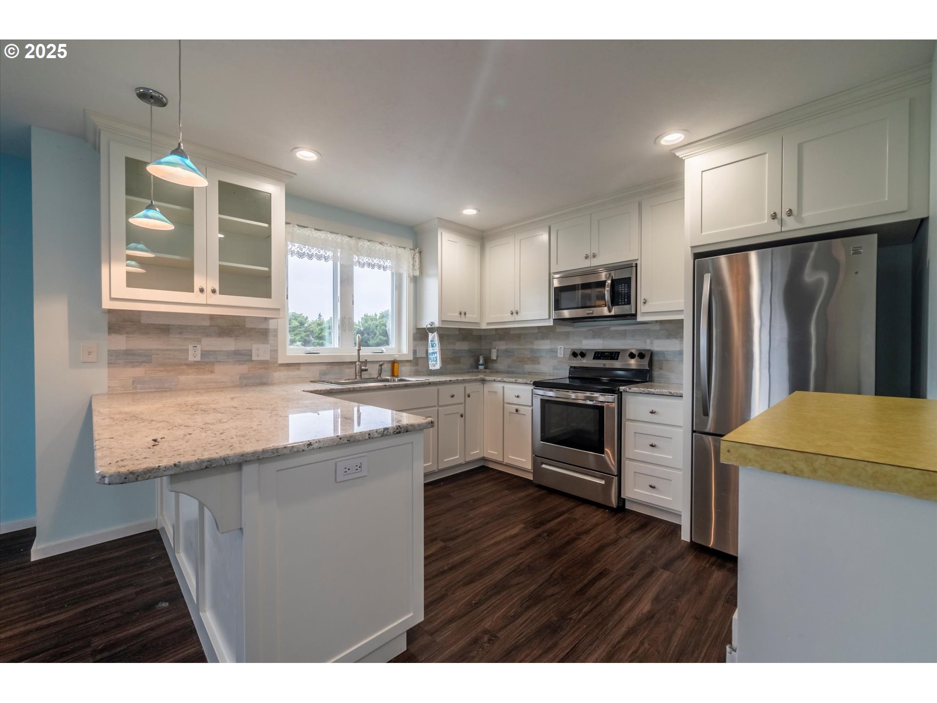 3145 Periwinkle Lane Southwest Bandon, OR 97411 - Photo 13 of 26 a kitchen with granite countertop a refrigerator a stove top oven a sink and dishwasher with wooden floor
