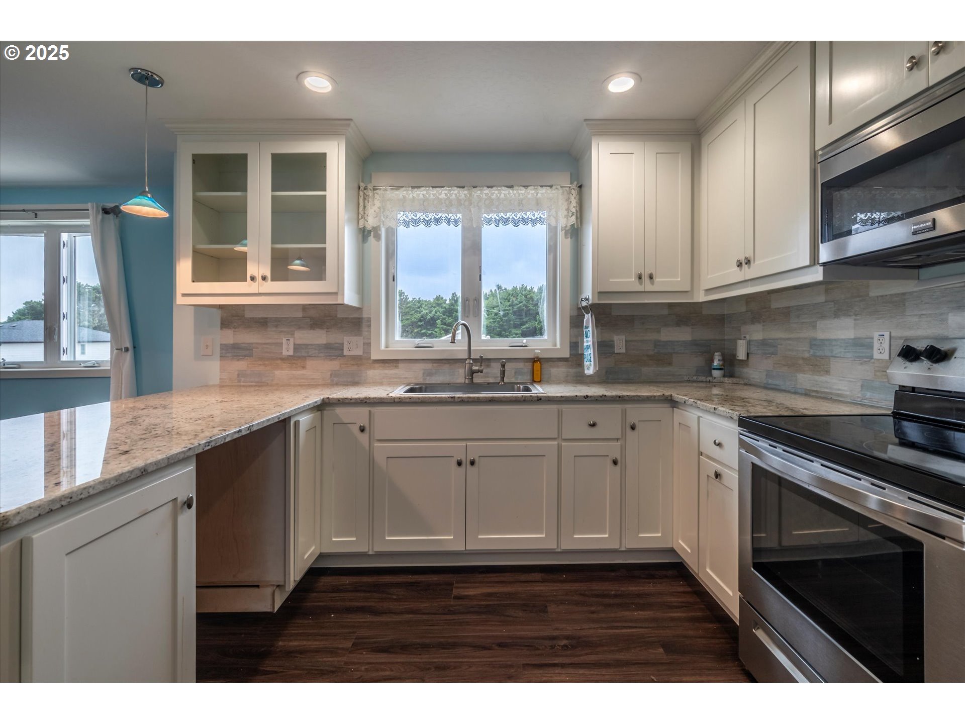 3145 Periwinkle Lane Southwest Bandon, OR 97411 - Photo 14 of 26 a kitchen with granite countertop wooden cabinets a sink a window and stainless steel appliances