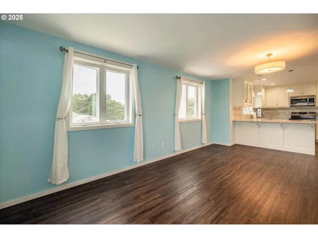 a view of an empty room with window and wooden floor