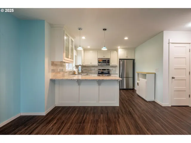 a open kitchen with kitchen island a sink dishwasher a refrigerator and a stove with wooden floor