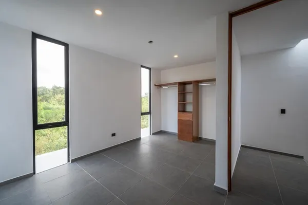 a view of an empty room with a window and a kitchen