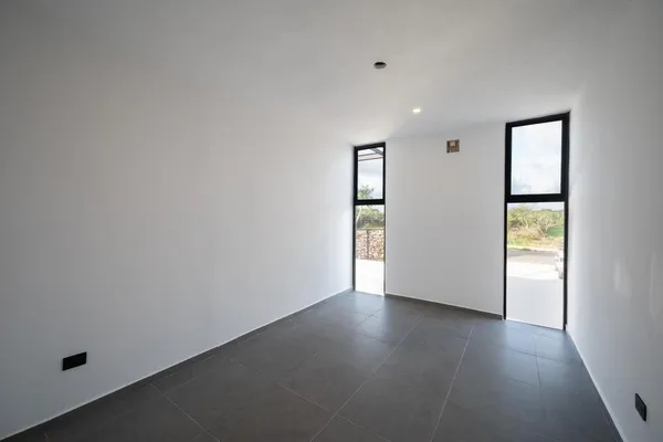 an empty room with wooden floor and windows with curtains