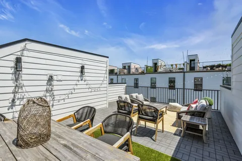 a roof deck with table and chairs and potted plants