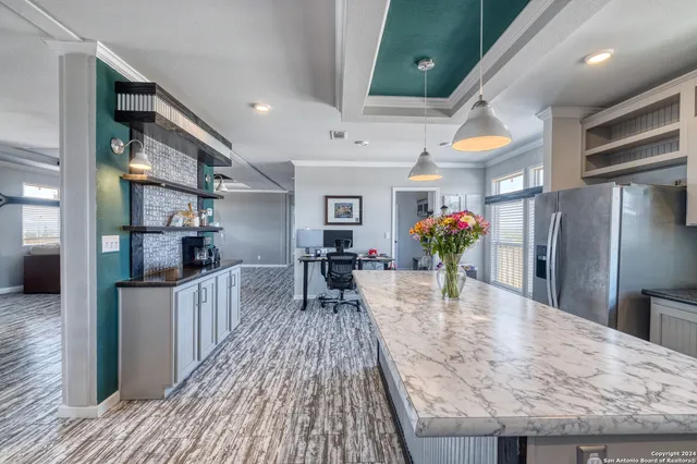 a kitchen with stainless steel appliances kitchen island granite countertop a refrigerator a stove and a wooden floors