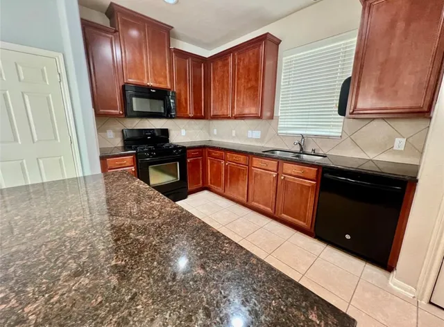 a kitchen with stainless steel appliances granite countertop wooden cabinets a stove top oven a sink and dishwasher