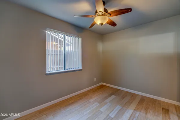 an empty room with wooden floor fan and windows