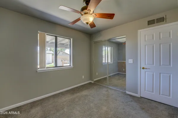 an empty room with windows and fan