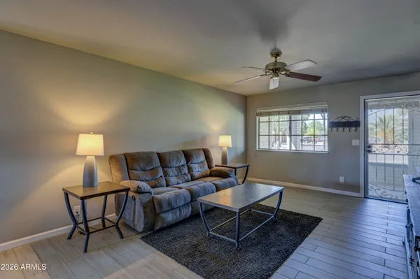 a living room with furniture a ceiling fan a lamp and a window