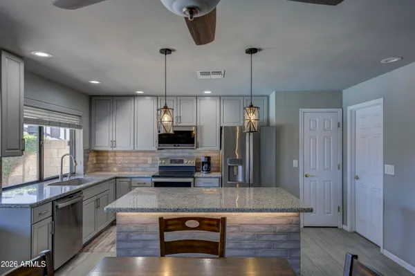 a kitchen with kitchen island stainless steel appliances a sink cabinets and wooden floor