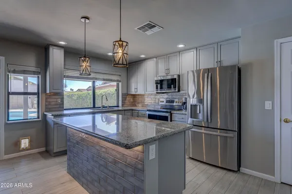 a kitchen with stainless steel appliances granite countertop a refrigerator a sink dishwasher a oven and a refrigerator with wooden floor