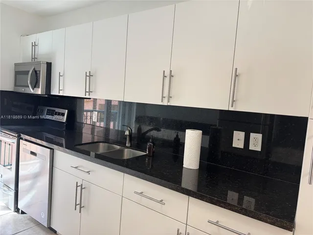 a kitchen with granite countertop white cabinets and black appliances