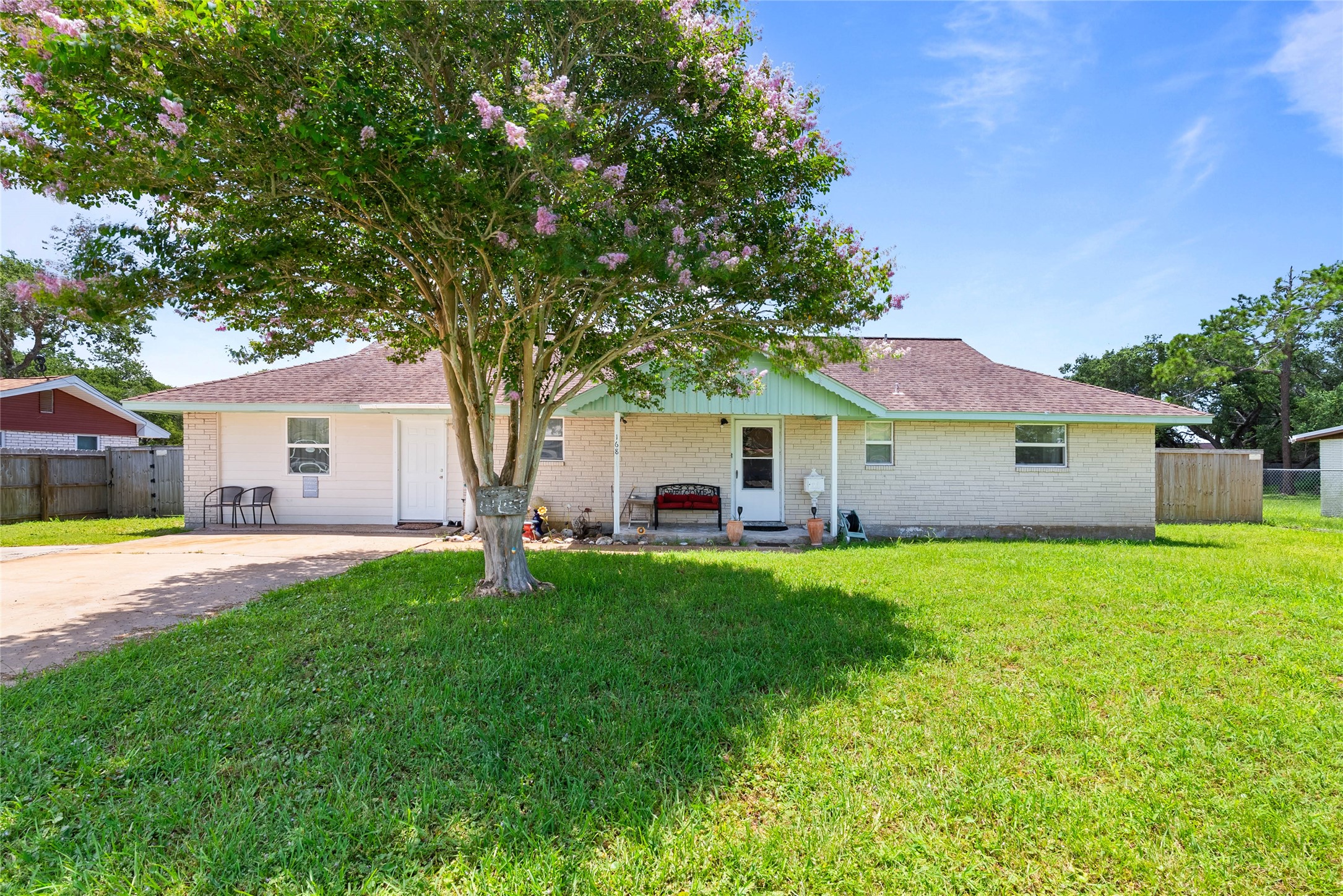 Front exterior view of the single-story home featuring a spacious front yard and mature shade trees.