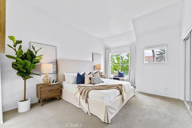 a bedroom with a bed a couch and a potted plant