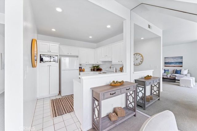 a kitchen with stainless steel appliances a refrigerator a sink a stove and white cabinets with wooden floor