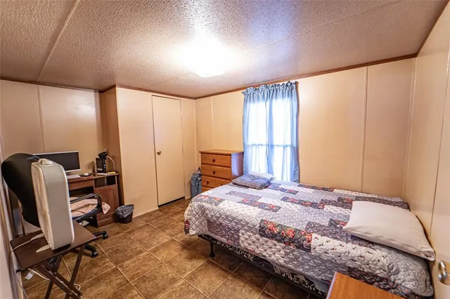 a bedroom with a bed a desk chair and a window