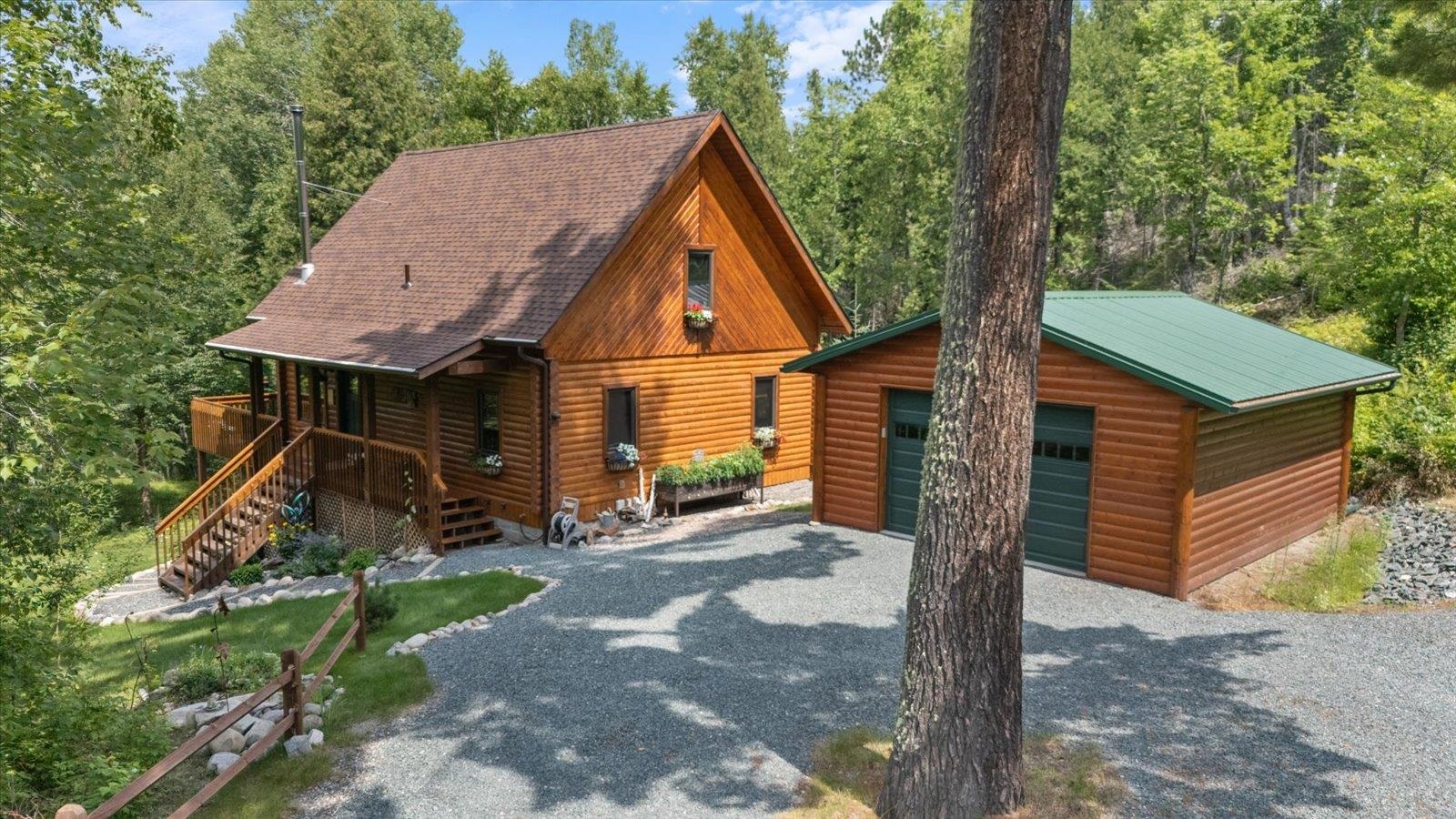 540 Loop Road Ely, MN 55731 - Photo 18 of 20 View of front of home featuring an outdoor structure, stairway, faux log siding, a shingled roof, and a detached garage