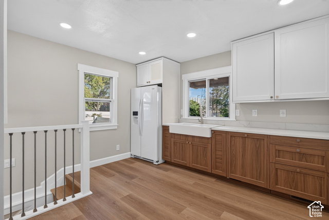 147 Center Street Clearfield, UT 84015 - Photo 30 of 55 Wood-finish flooring, two-tone cabinetry with white upper cabinets and wood-finish lower cabinets, white farmhouse sink with a chrome faucet, white countertops, and recessed lighting