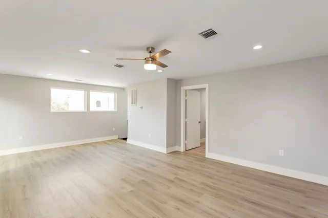 an empty room with wooden floor and windows