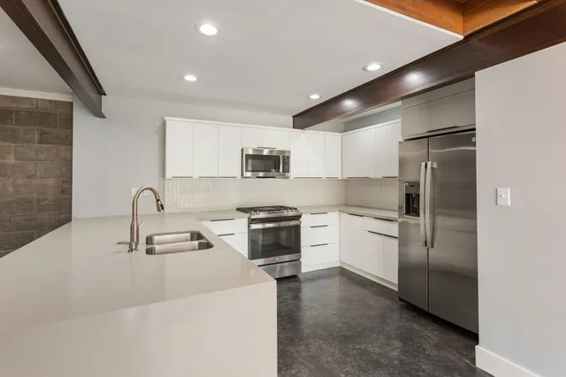 a kitchen with white cabinets stainless steel appliances and sink