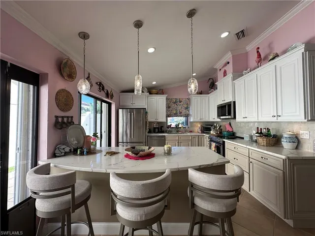 a kitchen with kitchen island granite countertop a sink a stove a dining table and chairs