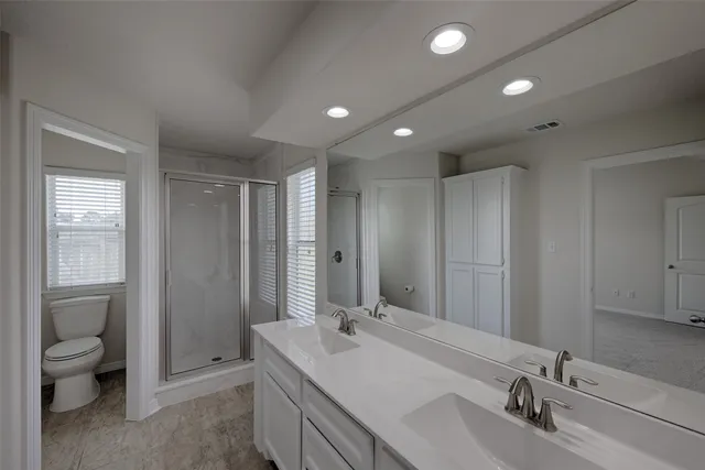 a bathroom with a double vanity sink toilet and shower