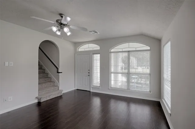 an empty room with wooden floor chandelier and windows