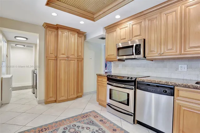a kitchen with granite countertop white cabinets and stainless steel appliances