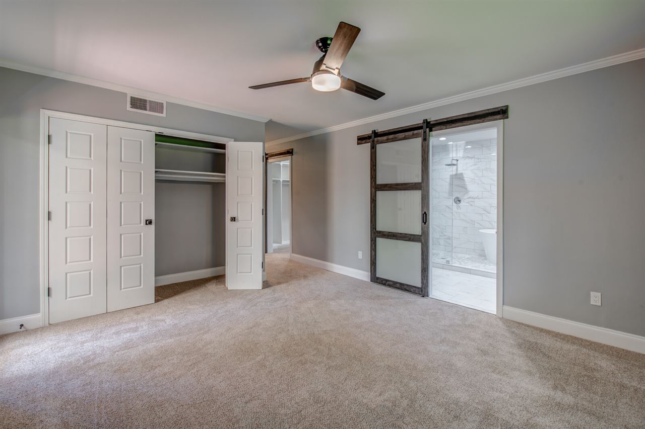 5209 South Angela Road Memphis, TN 38117 - Photo 18 of 25 Large master bedroom featuring his and her closets, barn doors, patio access, and a fabulous bathroom.