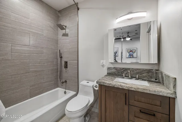 a bathroom with a granite countertop bathtub shower sink vanity mirror and toilet