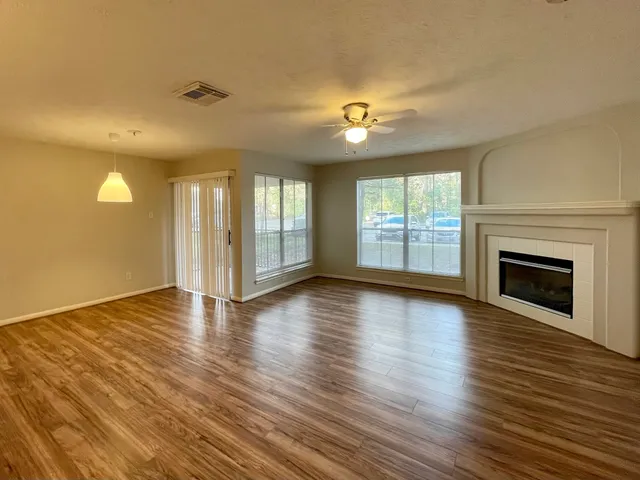 an empty room with wooden floor fireplace and windows