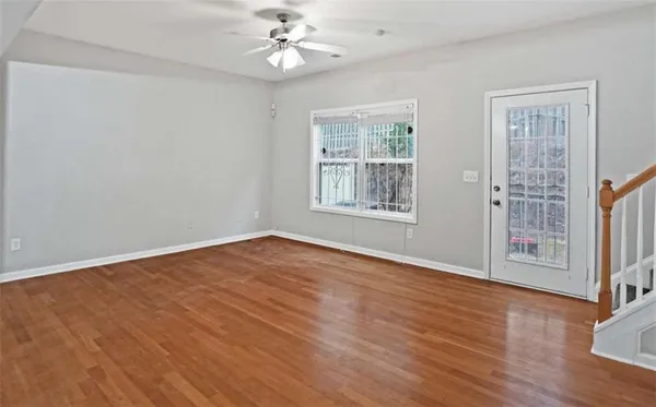 a view of an empty room with wooden floor and a window
